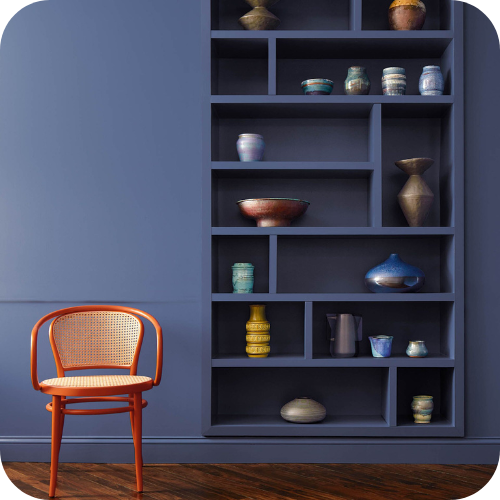 Benjamin Moore's Blue Nova paint color on a wall and bookcase with a red chair in front.