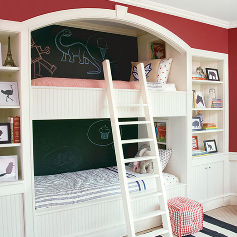 A child's bedroom showing bunk beds in the wall, with the back wall painted with Benjamin Moore's Chalkboard paint, showing dinosaurs and a cupcake drawn in chalk.