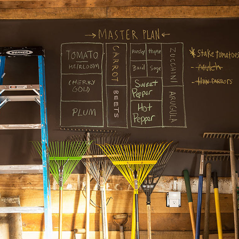 A garage wall that has been painted with Benjamin Moore's Chalkboard Paint, showing a list of vegetables to be planted in a garden.